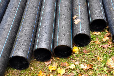 建筑现场的彩色抽象塑料管。工业设施的概念。红色 Pvc 水管特写。沟槽铺设电线用塑料安全软管